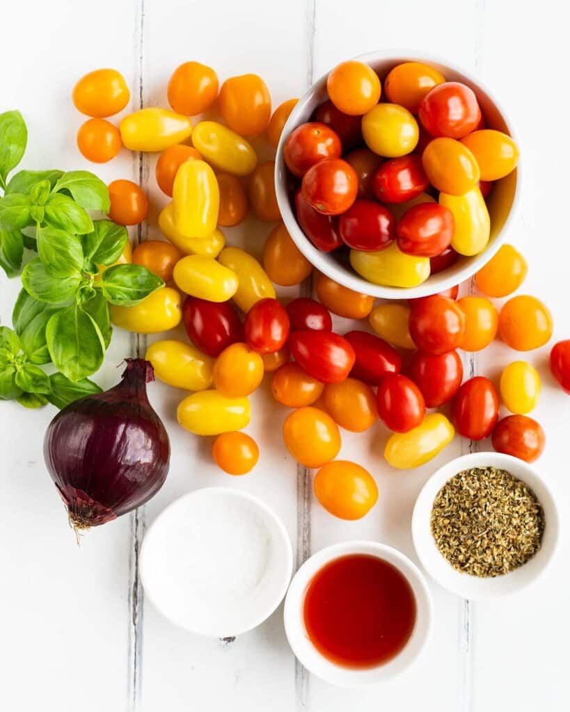 Ingredients required: baby tomatoes, red onion, olive oil, red wine vinegar, dried oregano, salt, basil and chives. Recipe by jaz kitchen